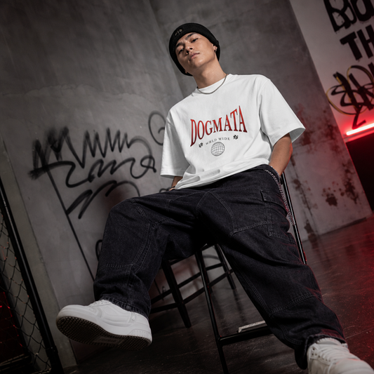 Person wearing a white 'Dogmata' t-shirt sitting on a chair against a graffiti-covered wall.
