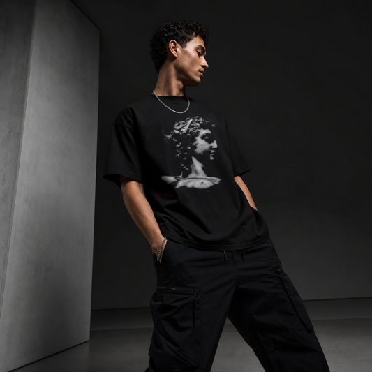 Person wearing a black t-shirt with a graphic design in a dark room