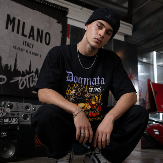 Person wearing a black t-shirt with 'Doomata Studios' design, sitting in an urban setting.